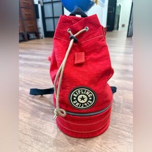 Kipling Vibrant Red Drawstring Backpack with bottom zip section.